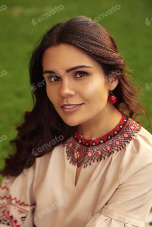 Preview: Beautiful woman wearing ornate beaded necklace and red earrings outdoors. Ukrainian national jewelry