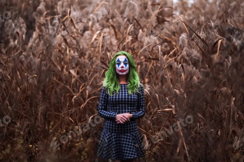 Preview: Portrait of a greenhaired girl with joker makeup on a orange leaves background.