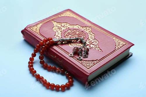 Preview: Muslim prayer beads and Quran on light blue background