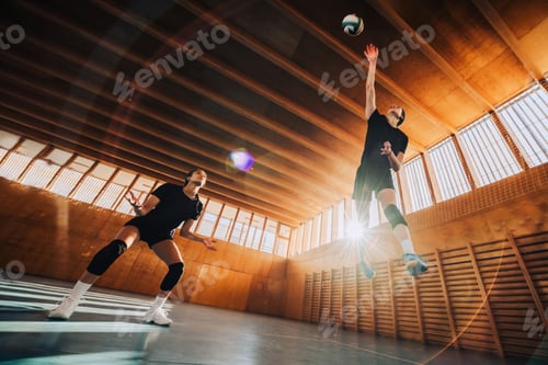 Preview: Low angle view of a volleyball players in action hitting a ball.