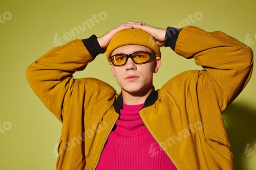 Preview: Fashionable young man showcases trendy style in studio setting with vibrant background