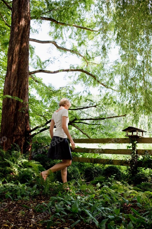 Preview: Young woman walking in garden
