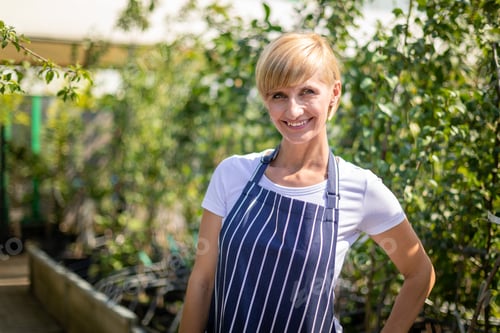 Preview: Proud gardener woman who is employee in garden center