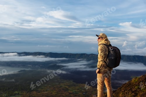 Preview: Man tourist looks at the sunrise on the volcano Batur on the island of Blai in Indonesia.