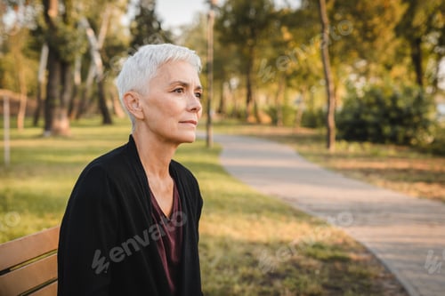 Preview: Contemplative Elderly Woman Relaxing on a Park Bench in Autumn