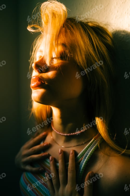Preview: Portrait of attractive caucasian woman with blonde hair posing in sunset light indoor.