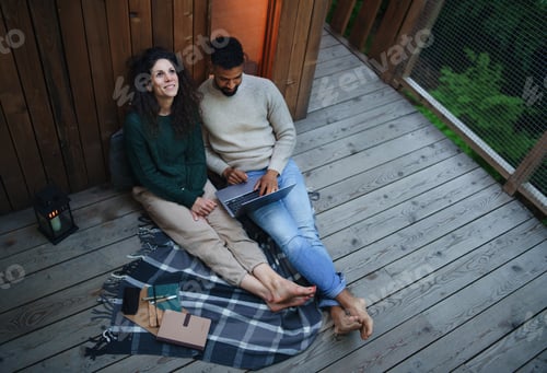 Preview: Couple with laptop resting outdoors in a tree house, weekend away and remote office concept.