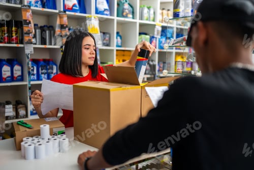 Preview: Woman checking a list and packing car parts into a cardboard box for a customer