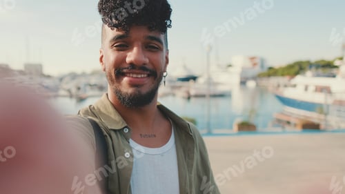 Preview: Young happy man with beard, dressed in an olive-colored shirt smiles and takes selfie