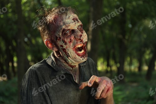 Preview: Scary zombie with bloody face outdoors. Halloween monster