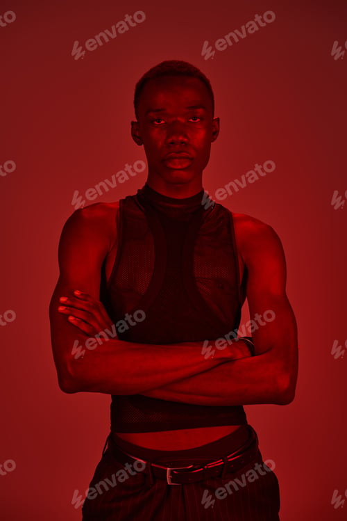 Preview: Vibrant young man exudes confidence in stylish attire against a dramatic red backdrop