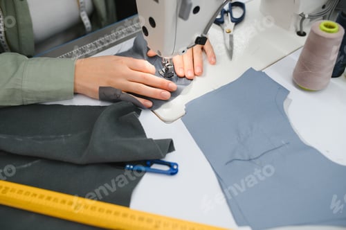 Preview: Young woman working as seamstress in clothing factory.