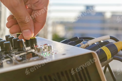Preview: close-up of male hand controlling audio input volume on music mixing panel