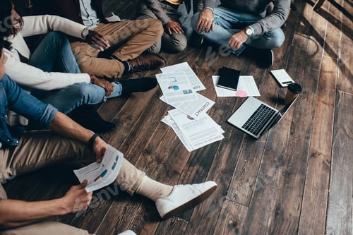 Preview: cropped view of multiethnic group of colleagues sitting on floor and working together on new project