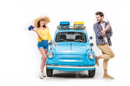 Preview: young tourists standing by car and holding flying tickets isolated on white