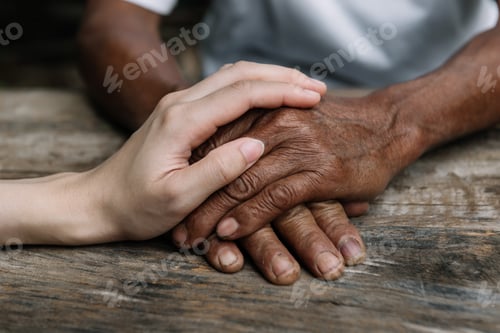 Preview: Hands of the old man and a woman hand on the wood table in sun light
