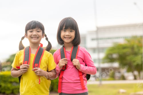 Preview: Back to school. Two cute asian child girls with school bag holding a book together in the school