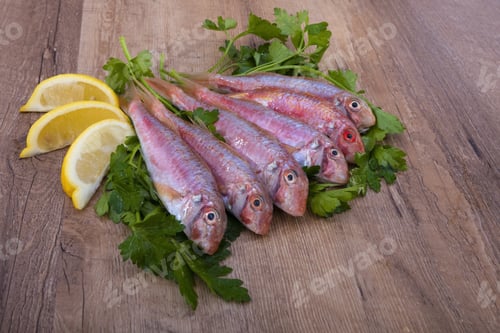 Preview: Closeup shot of raw fish with greens and lemon on the table