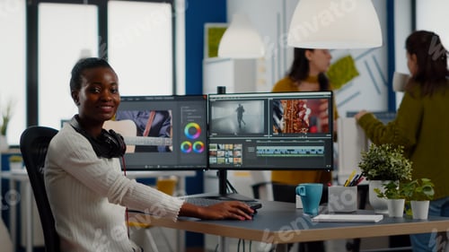 Preview: African video editor looking at camera smiling editing video project