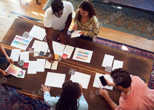 Preview: Overhead View Of Team Having Creative Design Meeting Around Wooden Table In Office
