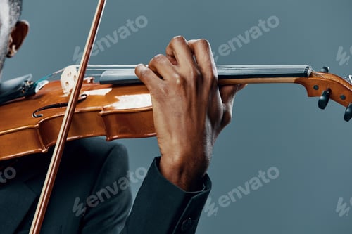Preview: Elegant African American man playing the violin in a tuxedo on a gray background