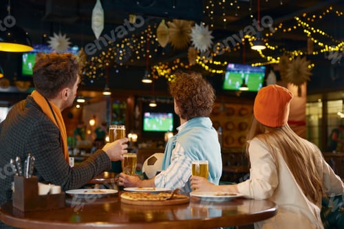 Preview: Group of friends watching football match on tv in pub