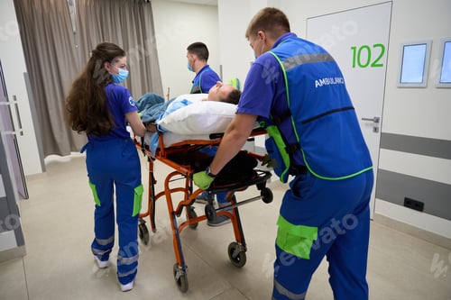 Preview: Paramedics carry a gurney with a patient along hospital corridor