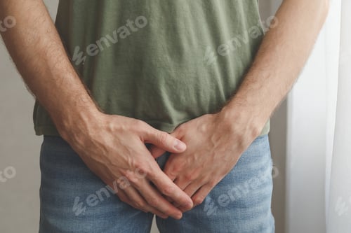 Preview: Man cover his groin by hands. Men's health. Urology problems male