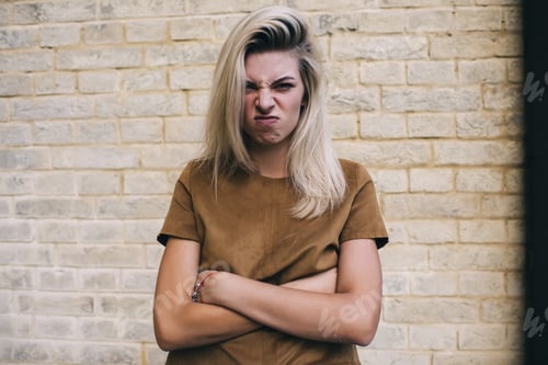 Vista previa: Young woman with folded hands standing near brick wall