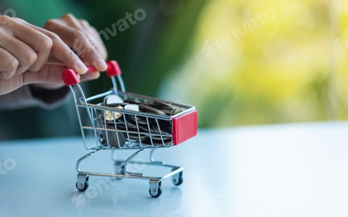 Preview: Hands holding a small shopping cart full of coins for saving money and financial concept