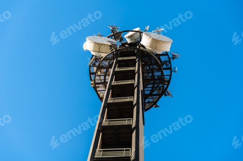 Preview: Telecommunications tower isolated on blue sky background, with dozens of antennas.