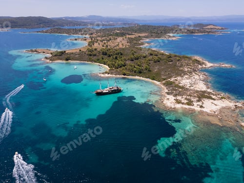 Preview: Aerial view of a coastal landscape with turquoise waters, sandy beaches, and a sailing ship anchored