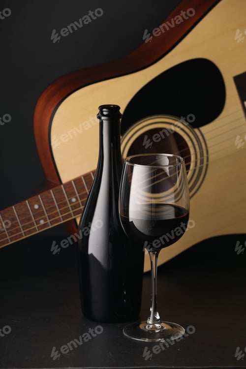 Preview: Acoustic guitar and red wine on black table, closeup