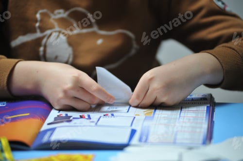 Preview: Female gluing soccer player stickers in a soccer album