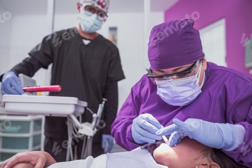 Preview: Mexican female dentist doing dental treatment on a young girl while the male assistant is watching