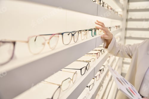 Preview: Woman consultant selects the right frames on the display window