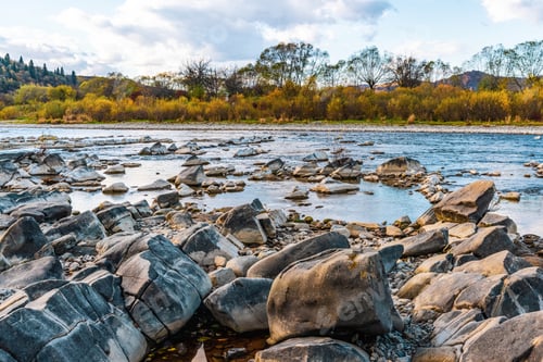 Preview: Stone bank against colorful trees growing on hills in autumn