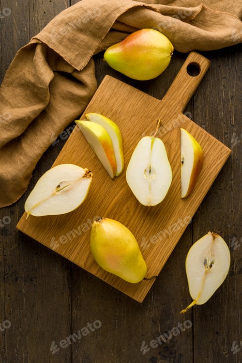 Preview: Sliced green pears on wooden cutting board. Food background vertical