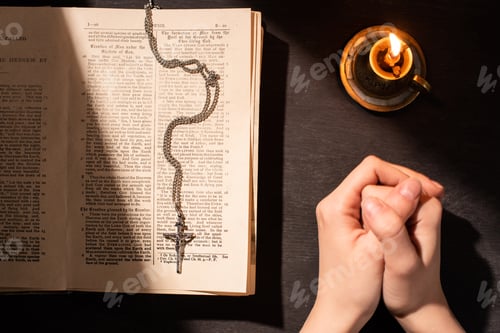 Preview: KYIV, UKRAINE - JANUARY 17, 2020: cropped view of woman praying near holy bible with cross, candle