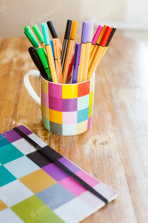 Preview: Marker and felt tip pens in desk organizer by book on wooden table