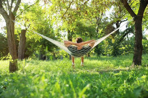 Preview: Young man resting in comfortable hammock at green garden