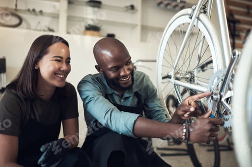 Preview: I fixed that. Shot of two young business owners crouching in their shop and fixing a bicycle wheel.