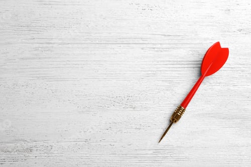 Preview: Red dart arrow on white wooden table, top view with space for text