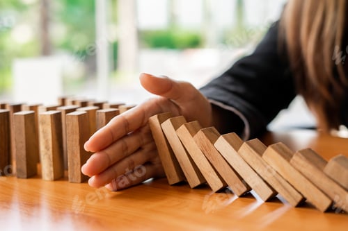 Preview: A businesswoman blocks a falling wooden block like a domino. It is like stopping business risks with