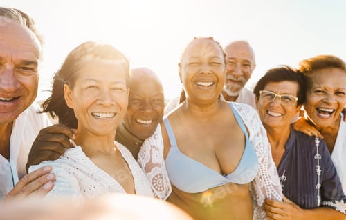 Preview: Happy senior people having doing selfie on the beach at sunset time while wearing summer clothes