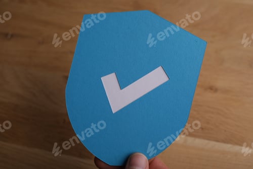 Preview: Closeup shot of a man holding a blue protection shield icon with a white checkmark on it