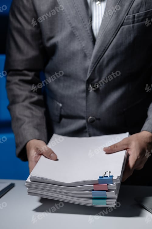Preview: An employee was tidying up a pile of documents piled on his desk before returning home from work, A