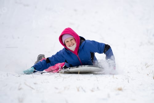 Preview: Happy child rides a sled down a snowy slope