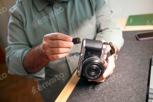 Preview: Man inserting memory card into camera.