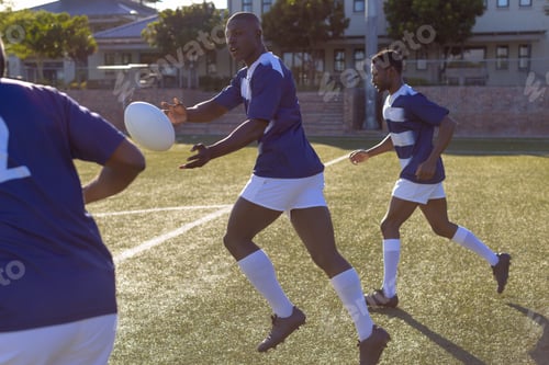 Preview: Three African American young male athletes are playing rugby on field outdoors